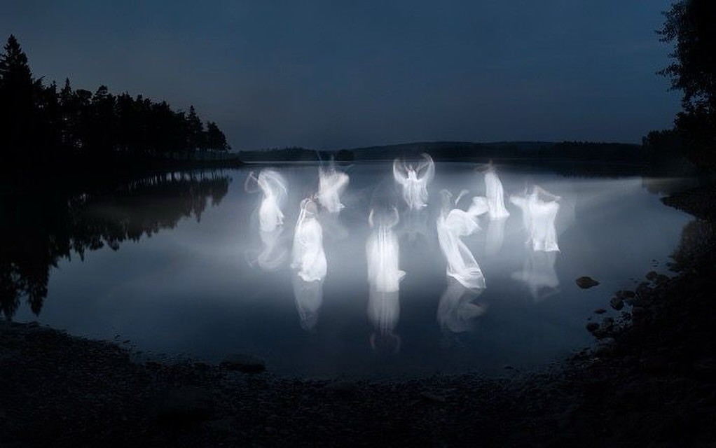 An old Volvo car with a lake and mountains in the background